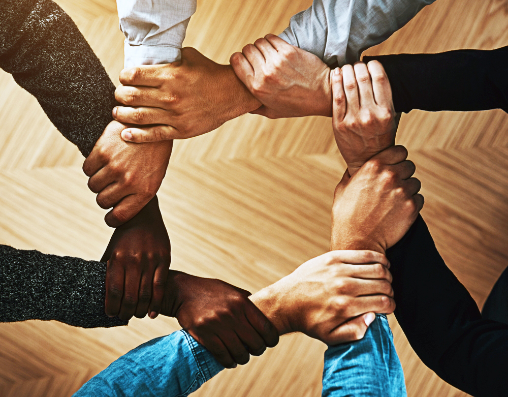Solidarity, holding or hands of business people with diversity for group support or teamwork in office. Community, link or above group of employees with mission or team building for goals together